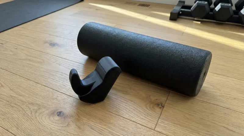 Core Nexus psoas and iliacus release tool next to a foam roller — showing the difference between targeted precision and broad surface pressure
