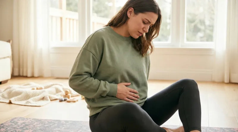 Young mother sitting on a yoga mat working on postpartum pelvic tension — the psoas and iliacus muscles may be the missing piece in recovery